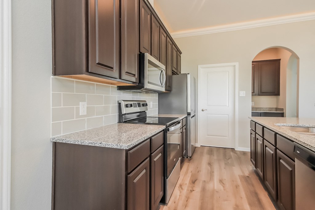an empty kitchen with black appliances and granite counter tops