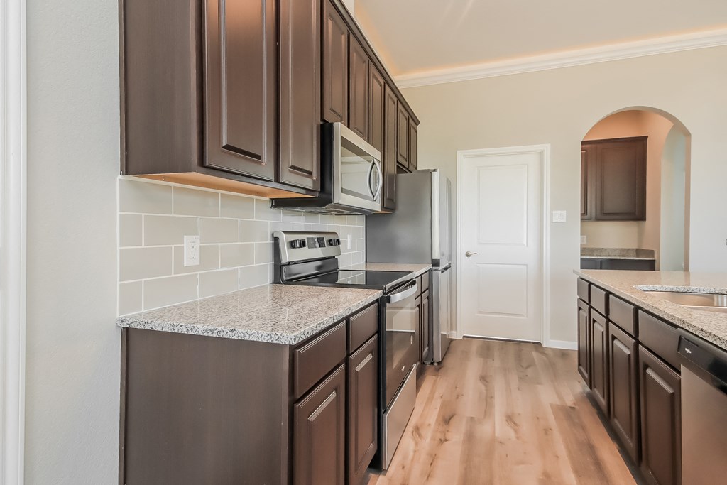 an empty kitchen with black appliances and granite counter tops