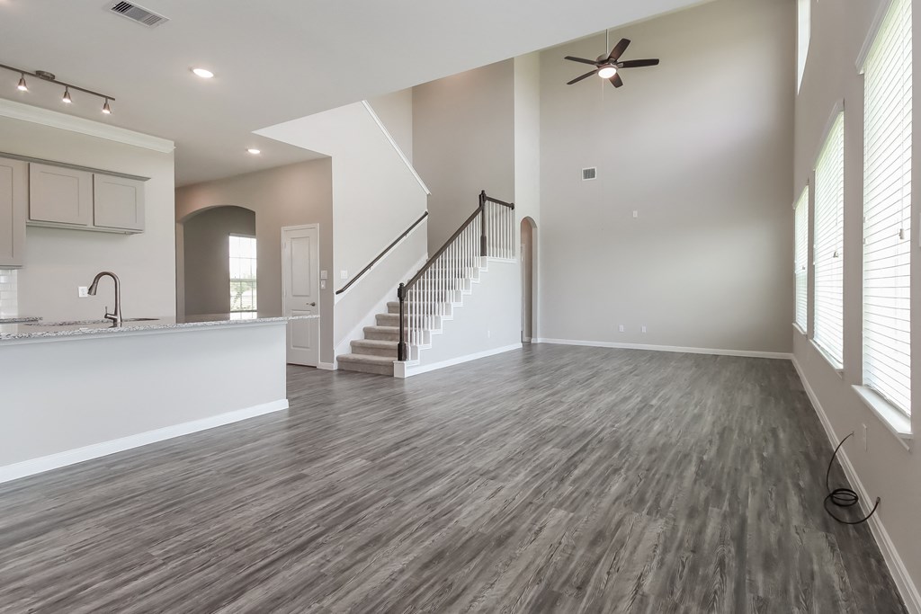 an empty living room with a staircase and a kitchen