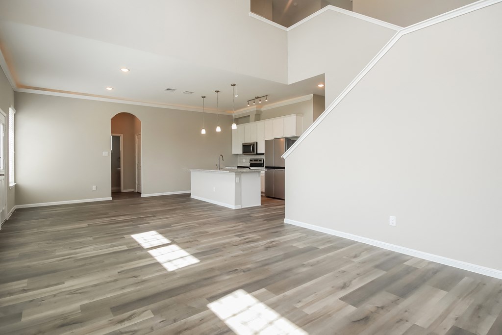 an empty living room and kitchen with wood flooring