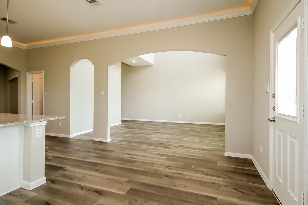 an empty living room with a hard wood floor and white walls