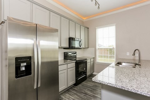 A modern kitchen with a stainless steel refrigerator and black appliances.