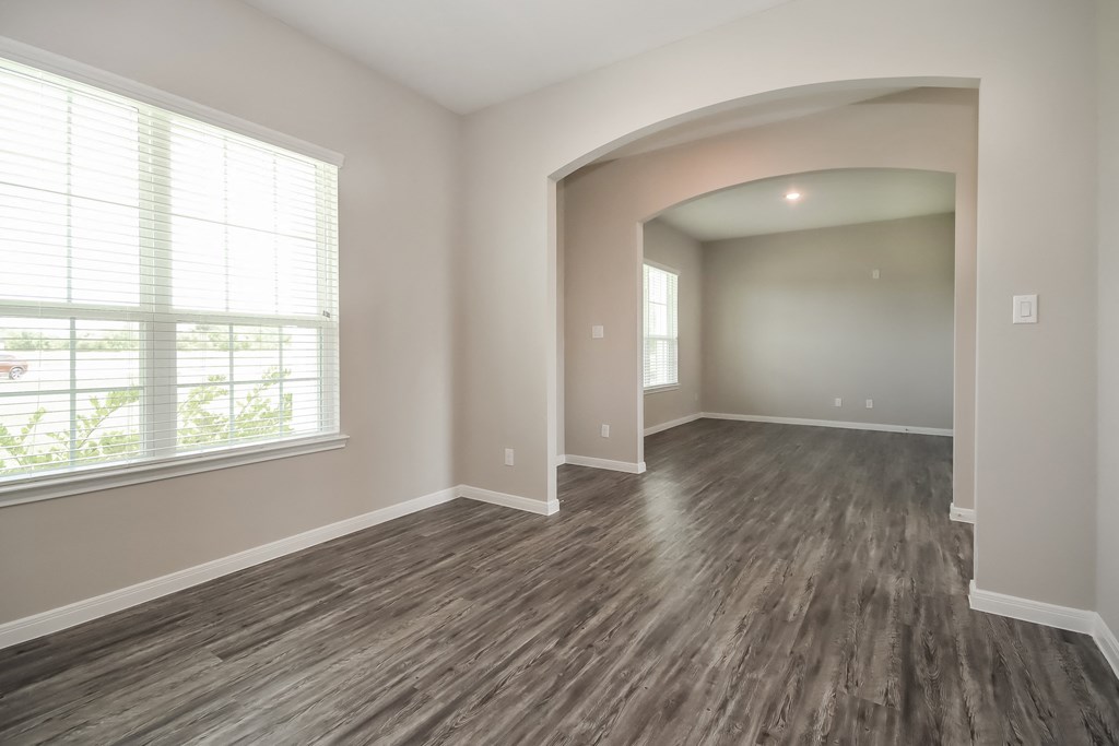 an empty living room with wood flooring and a large window
