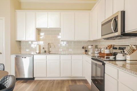 A kitchen with white cabinets and a black fridge.