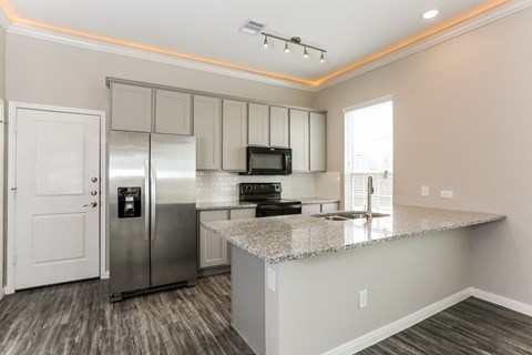 A kitchen with a refrigerator, microwave, and stove top oven.