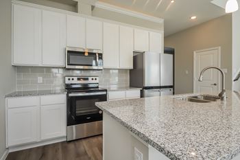 a kitchen with white cabinets and a granite counter top