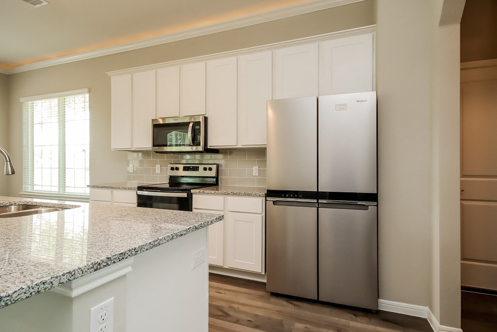 a kitchen with white cabinets and stainless steel refrigerator