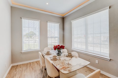 a dining room with a table and chairs and two windows