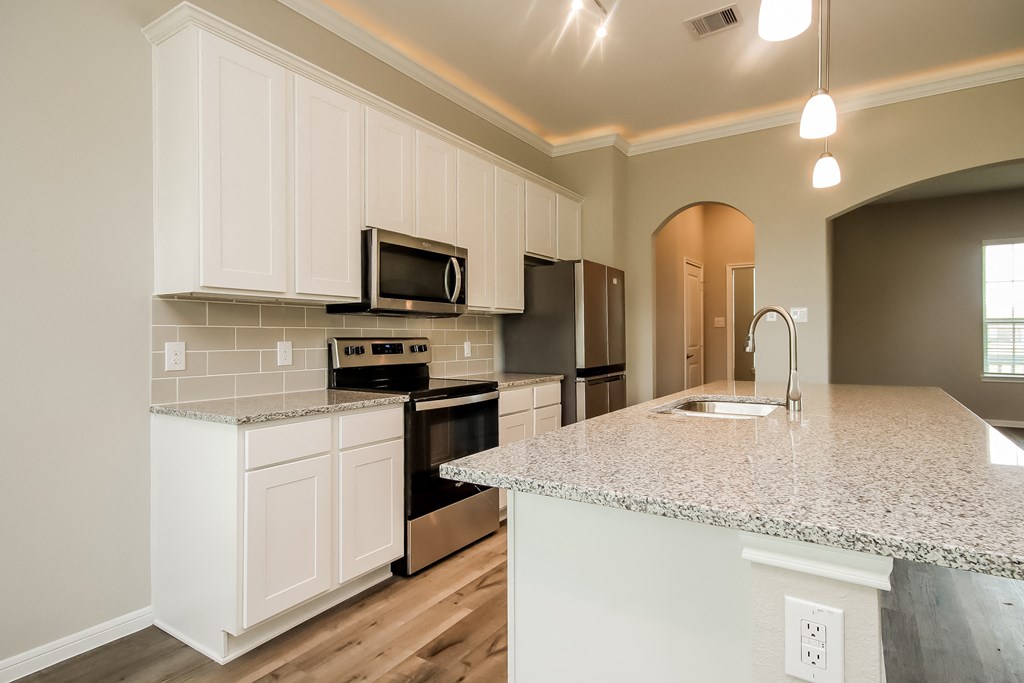 a kitchen with white cabinets and a marble counter top