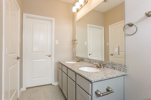 A bathroom with a sink, mirror, and cabinets.