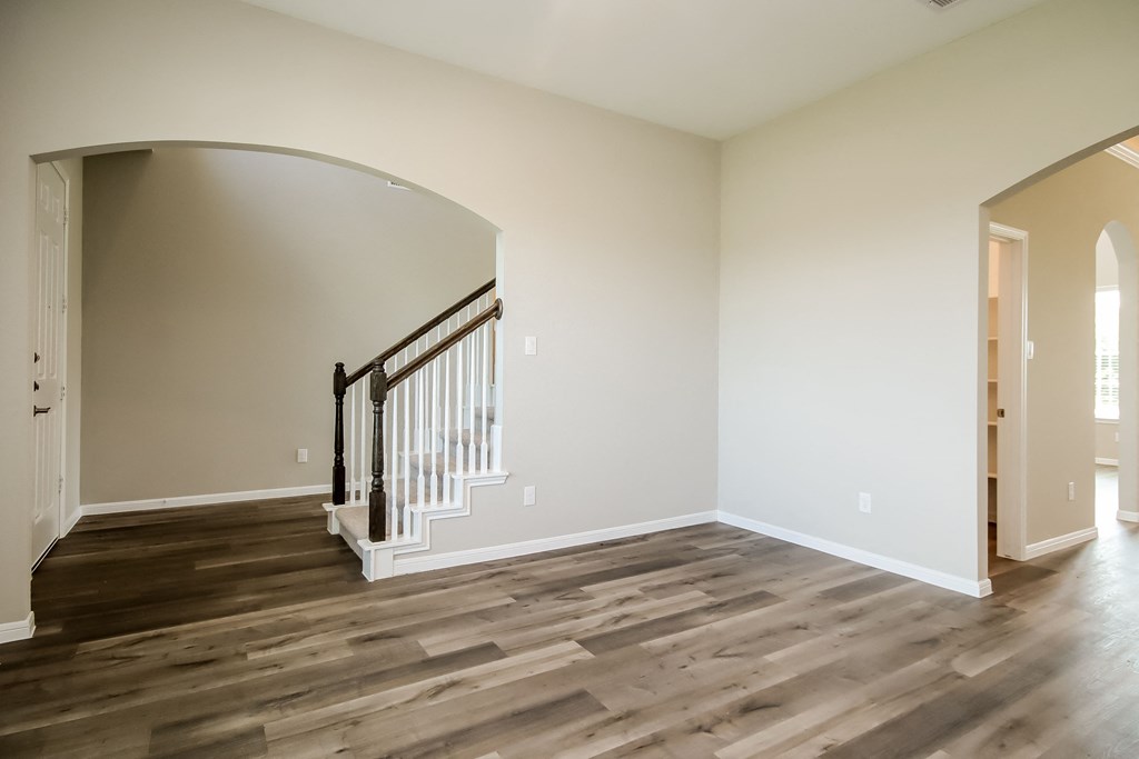 an empty living room with hard wood floors and a staircase