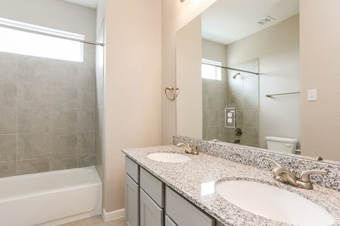 A bathroom with a white tub, sink, and tiled shower.