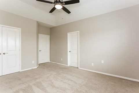 A room with a ceiling fan and carpeted floor.