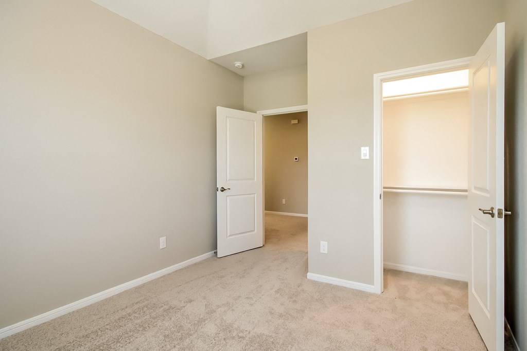 an empty bedroom with an open door and a closet
