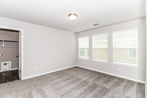 an empty bedroom with three windows and a closet