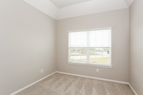 A room with a window and a carpeted floor.