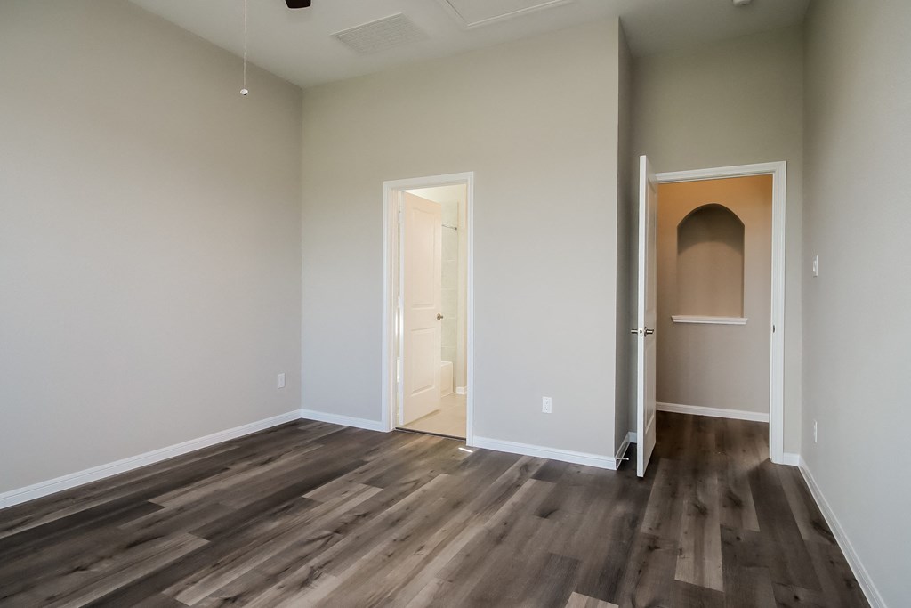 an empty living room with wooden floors and a door to a hallway