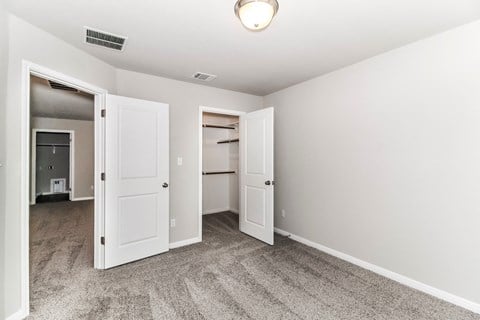A room with a carpeted floor and two open doors.