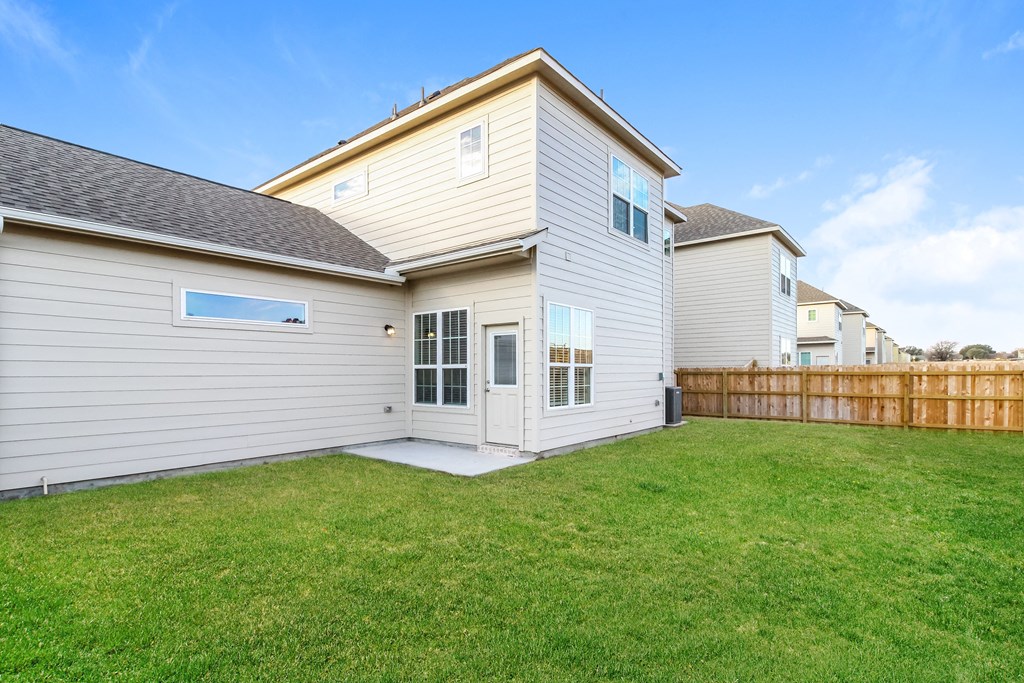 a backyard with green grass and a white house with a gray roof