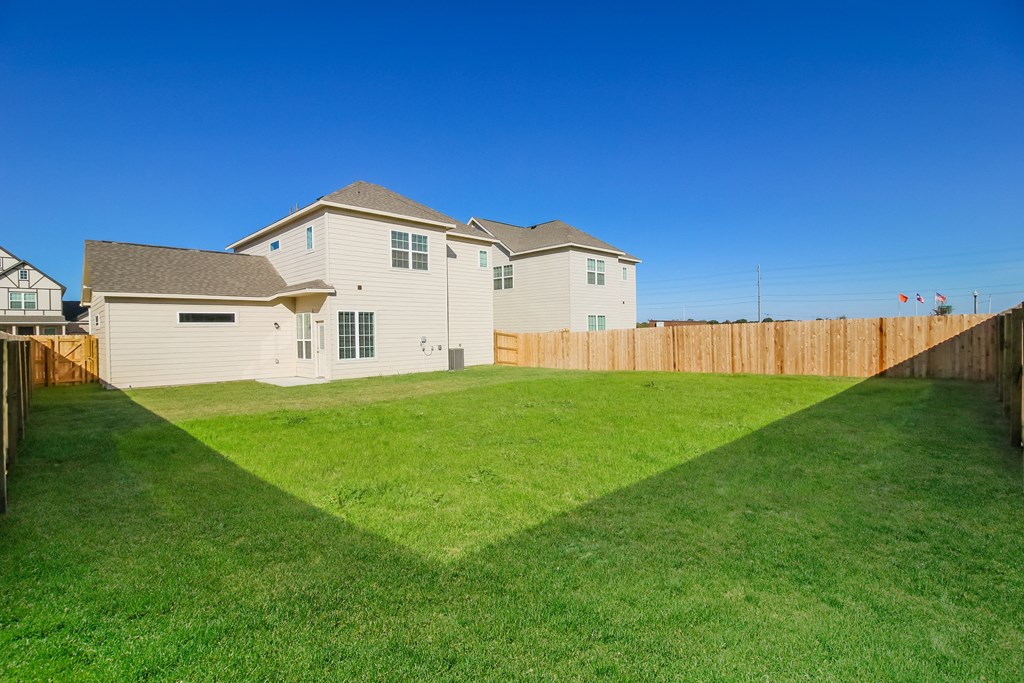 a backyard with green grass and a wooden fence