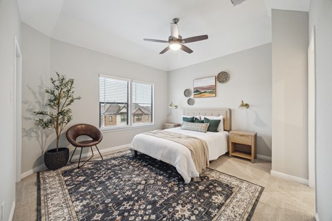 A bedroom with a bed, chair, and a rug.