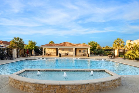 A large outdoor swimming pool with a fountain in the middle.