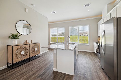 A kitchen with a white fridge and a round mirror on the wall.