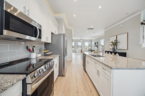 A modern kitchen with a black stove top oven and a silver microwave above it.