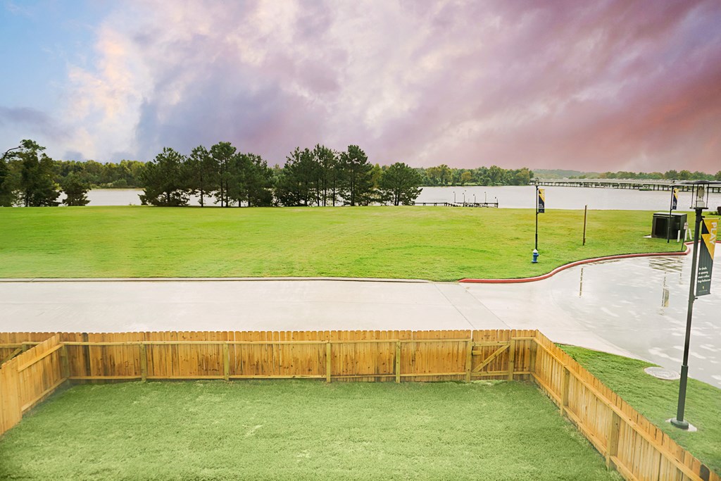 a view of a park with a lake and a fence