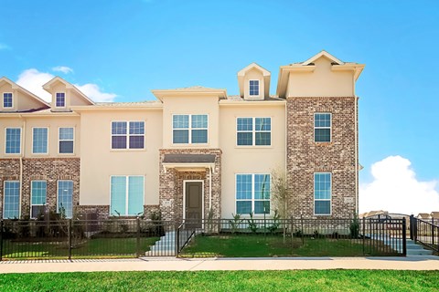 A large, two-story house with a black fence in front.