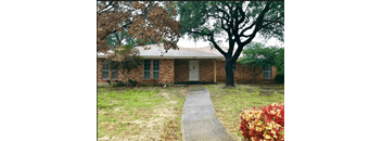 a small brick house with a sidewalk in front of it