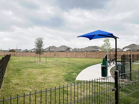 A blue umbrella is on a pole in a grassy area.
