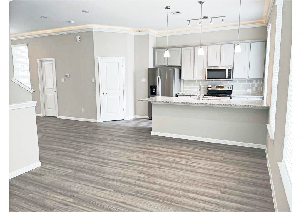 an empty kitchen and living room with wood floors