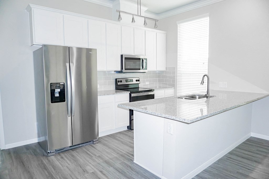 a kitchen with white cabinets and a stainless steel refrigerator