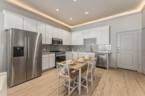 A modern kitchen with a dining table set for two.