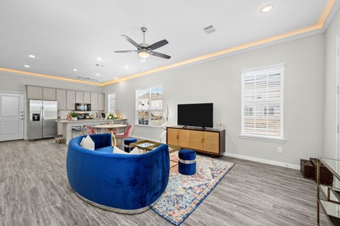 A blue velvet chair is in the middle of a living room.
