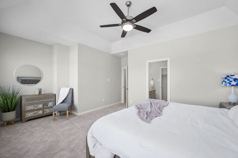 A bedroom with a bed, a ceiling fan, and a chair.