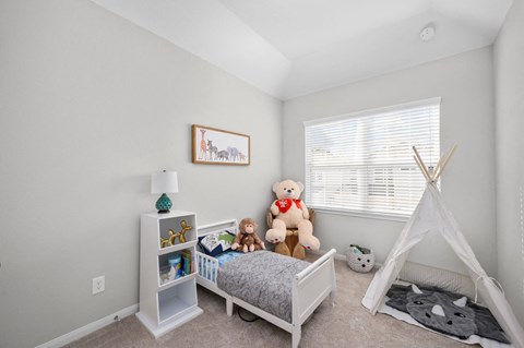 A child's bedroom with a white bed, a teepee, and a teddy bear.