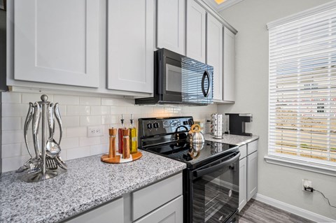 A kitchen with a black microwave above the stove.