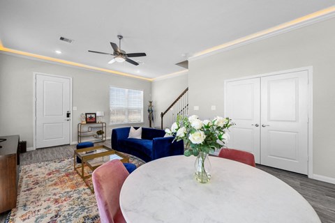 A living room with a white table and a vase of white flowers on it.