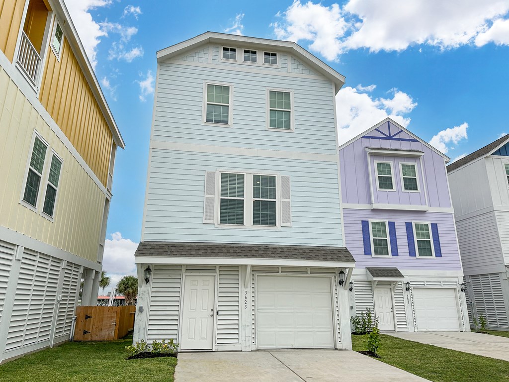 a white house with a garage in front of other houses