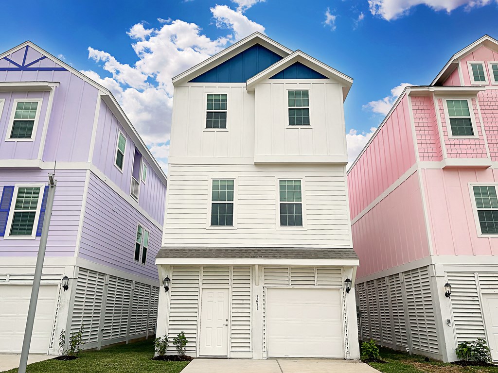 a row of white houses with pink and blue roofs