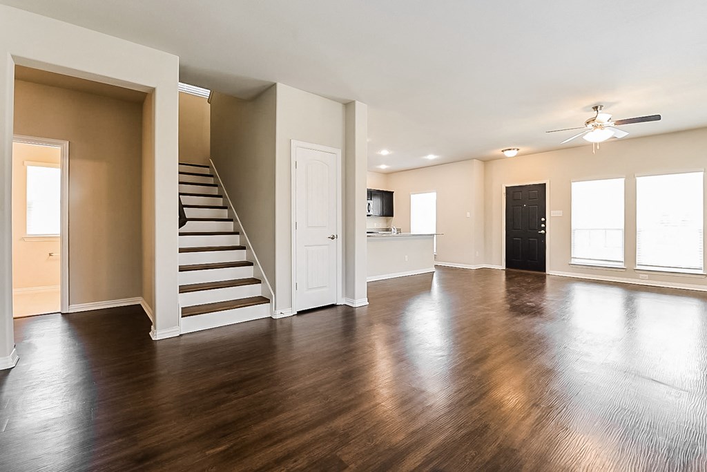 an empty living room with hard wood floors and a staircase