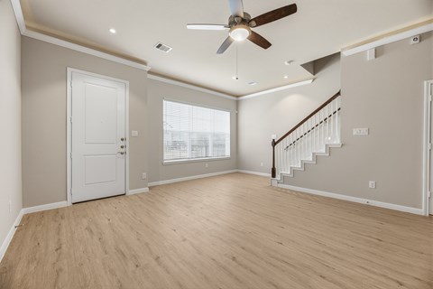 A spacious room with a staircase and a ceiling fan.