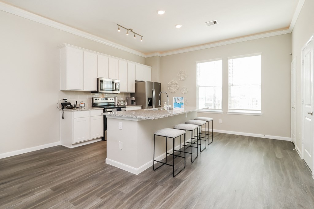 a kitchen with white cabinets and a large island with bar stools