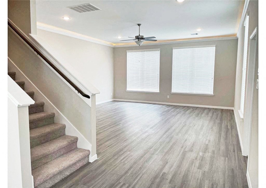 an empty living room with a staircase and a ceiling fan