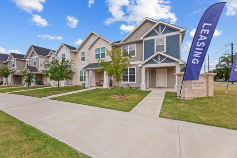 A row of houses with a leasing sign in front.
