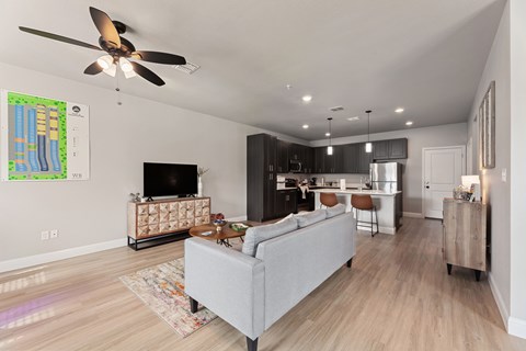 A living room with a grey couch and a ceiling fan.