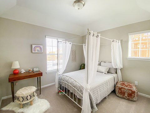 A bedroom with a white bed and a small table with a lamp and a red ball on it.