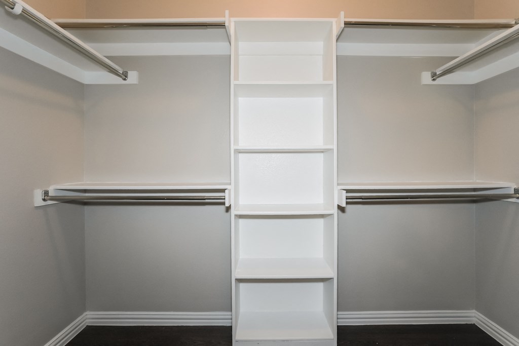 a walk in closet with white shelving and empty shelves